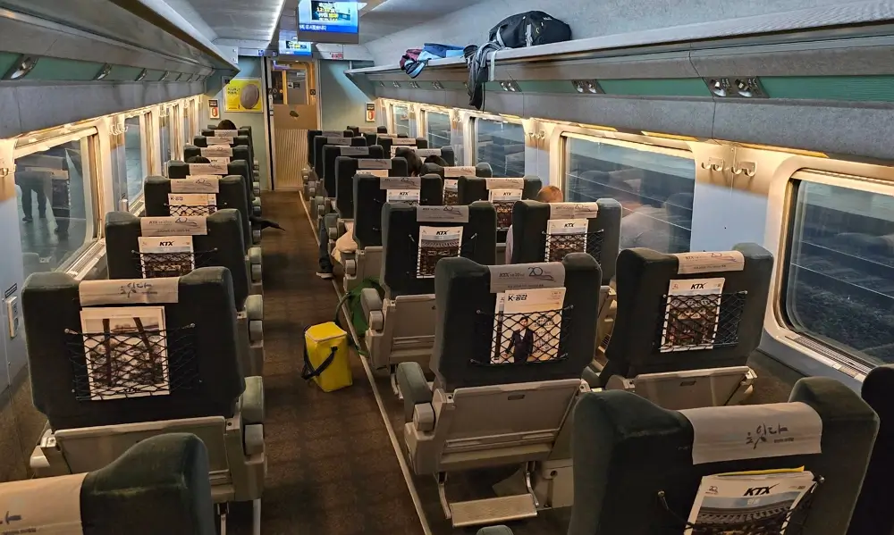 Interior view of a KTX train first class car featuring premium passenger seats and spacious aisle