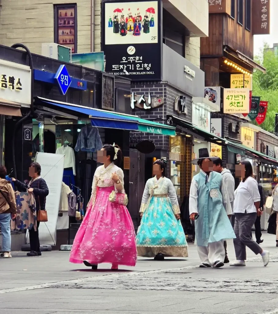 People wearing colorful traditional Korean Hanok dresses walking on the street of Insadong, Seoul, experiencing Korean culture.
