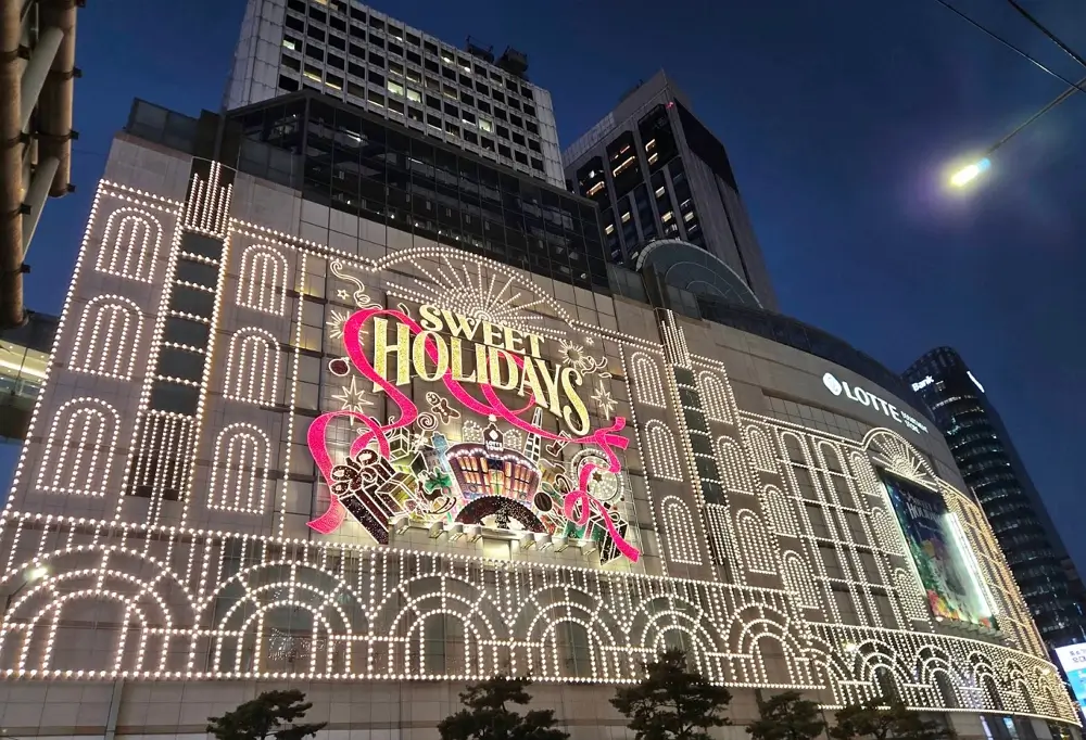 Stunning night view of Lotte Department Store Main Branch in Myeongdong, Seoul, illuminated with vibrant holiday light displays.