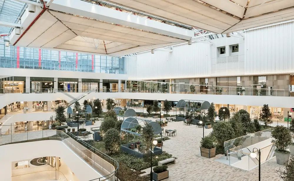 Futuristic indoor botanical garden aesthetic inside The Hyundai Seoul department store featuring massive glass ceilings and green trees.